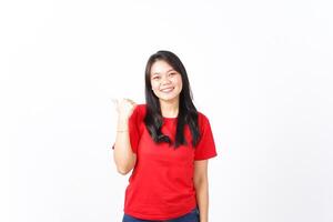Smiling while Showing and Pointing Product With Thumb Of Beautiful Asian Woman wearing red shirt Isolated On White Background photo