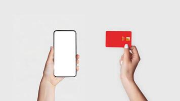 Internet shopping concept. Closeup of girl holdng credit card and mobile phone with blank screen on light background, mockup for design. Panorama photo