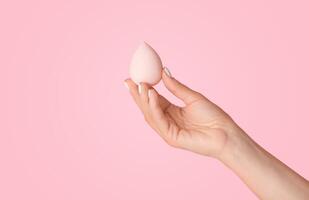 Woman showing cosmetic applicator on pink background, close up of hand. Panorama photo