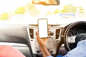 Back rear over the shoulder view of happy black male driver holding smartphone with blank screen, mock up. Closeup of mobile phone with empty display, couple using mobile app for navigation, copyspace photo