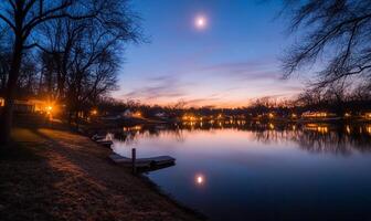 A lake at dusk with a moon and a boat photo