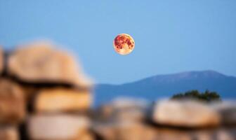 The moon rises over the mountains in the background photo