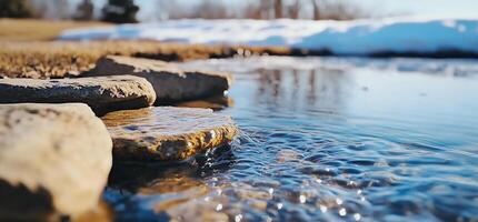 A stream of water flows over rocks in a field photo