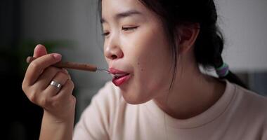 Handheld selective focus shot, Happy young woman enjoys eating Sukiyaki or Shabu Shabu hot pot with great relish on the table at home. Ready to eat video