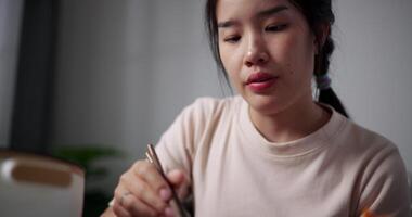 Handheld selective focus shot, Happy young woman enjoys eating Sukiyaki or Shabu Shabu hot pot with great relish on the table at home. Ready to eat video