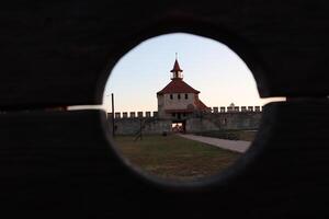 A Beautiful and Charming Castle Is Seen Through a Rustic Wooden Frame During the Stunning Dusk Time photo