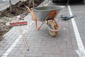 A Construction Site featuring a Wheelbarrow prominently placed alongside a Warning Sign photo