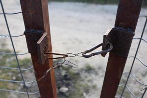 A rusty old fence gate with a simple locking mechanism that guarantees security and privacy photo