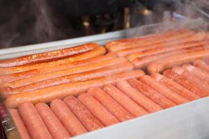Delicious Grilled Hot Dogs Served Fresh on a Steaming Food Cart for Everyone to Enjoy photo