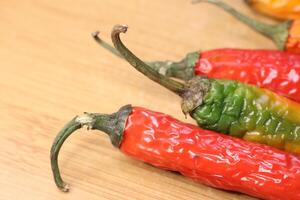 A Variety of Colorful and Aromatic Chili Peppers Displayed on a Rustic Wooden Surface photo