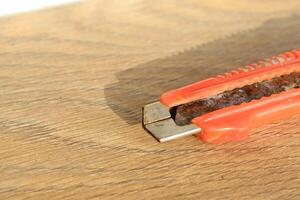 A CloseUp View of a Rusty Utility Knife Resting on a Wooden Surface for Contextual Detail photo
