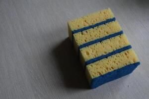 A Colorful Cleaning Sponge Resting on a Wooden Surface Ready for Household Tasks and Use photo