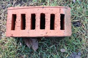 A Hollow Clay Brick resting on lush Green Grass, showcasing its rustic charm and texture photo