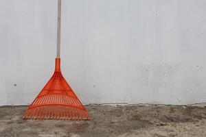 A Vibrant Orange Rake Placed Against a Simple Yet Striking Background for Context and Focus photo
