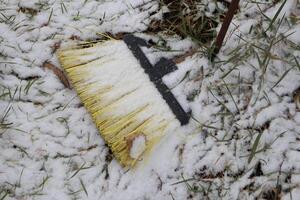 A SnowCovered Broom Left Abandoned on the Cold Ground Surrounded by the Wintery Landscape photo