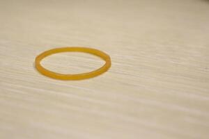 The image shows a yellow rubber band on a wooden surface, highlighting its features photo