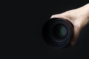 Camera lens in hand isolated on black background. copy space photo