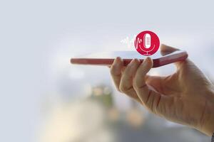 Voice recording. Hand holding microphone icon on smart phone. Mobile application Record sound, audio, music, voice message. or Use your voice to direct AI to search for information on Internet. photo