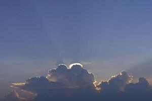 a large cloud with sun rays shining through it photo