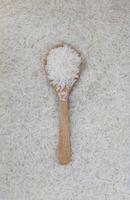Jasmine rice in a wooden spoon background, top view photo