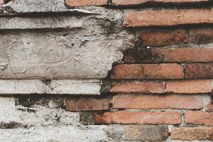 Old red brick wall with white stucco, paint and cracks. photo