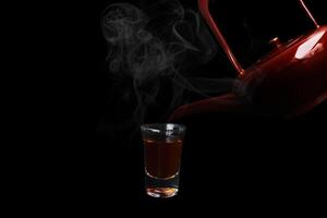 a teapot pours a shot of whiskey into a glass photo
