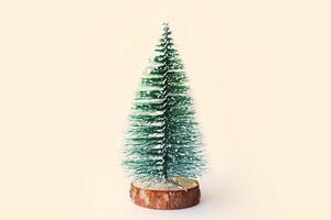 a small christmas tree is on a wooden base photo