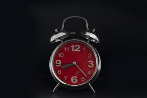 a red alarm clock on a black background photo