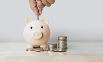 a hand putting coins into a piggy bank photo