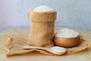 rice in a sack and wooden spoon on a wooden table photo