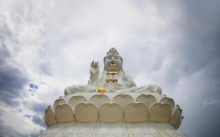 a white statue of buddha sitting on a large white base photo