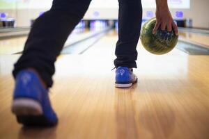 a person walking down a bowling alley with a bowling ball photo