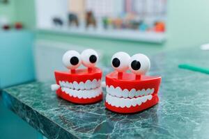 Miniatures of dental artificial jaws with eyes. A plastic model of teeth sits on a table in a dentist's office. photo