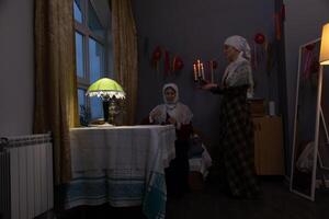 Two women in a room with a table and a lamp photo