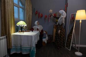 A woman in a headscarf standing next to a table photo