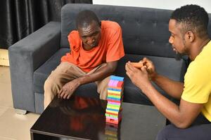 A warm and engaging scene of an amputee man and his friend enjoying a Board game with wooden bricks. Jenga game, wooden tower photo