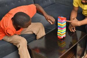 A warm and engaging scene of an amputee man and his friend enjoying a Board game with wooden bricks. Jenga game, wooden tower photo