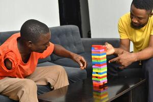 A warm and engaging scene of an amputee man and his friend enjoying a Board game with wooden bricks. Jenga game, wooden tower photo