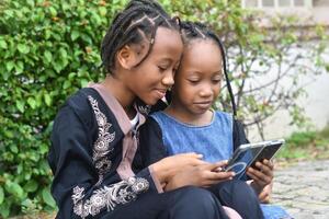 A heartwarming and lively image of two sisters enjoying their time together while using a cellphone. photo