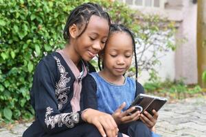A heartwarming and lively image of two sisters enjoying their time together while using a cellphone. photo
