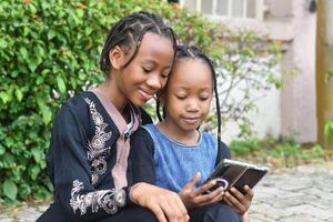 A heartwarming and lively image of two sisters enjoying their time together while using a cellphone. photo
