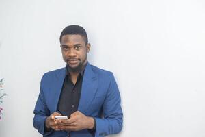 portrait of cheerful young black guy sending message on mobile phone. Happy African-American man using smartphone, enjoying chatting online, messaging in social networks photo