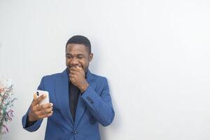 portrait of cheerful young black guy sending message on mobile phone. Happy African-American man using smartphone, enjoying chatting online, messaging in social networks photo