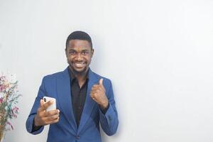 portrait of cheerful young black guy sending message on mobile phone. Happy African-American man using smartphone, enjoying chatting online, messaging in social networks photo