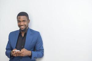 portrait of cheerful young black guy sending message on mobile phone. Happy African-American man using smartphone, enjoying chatting online, messaging in social networks photo