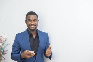 portrait of cheerful young black guy sending message on mobile phone. Happy African-American man using smartphone, enjoying chatting online, messaging in social networks photo