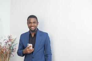 portrait of cheerful young black guy sending message on mobile phone. Happy African-American man using smartphone, enjoying chatting online, messaging in social networks photo