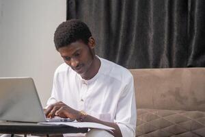 Working with papers. Serious african male entrepreneur work at home office alone hold read document hardcopy think on conditions terms. Focused young man engaged in paperwork edit text of agreement photo