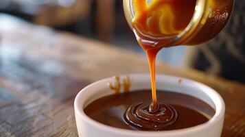 Stream of caramel sauce being poured from a jar into a bowl, gastronomy photography photo