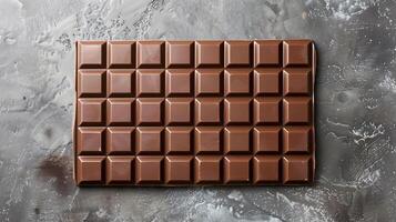 Plain chocolate bar laid flat on a surface, clearly divided into several equally sized squares, gastronomy photography photo